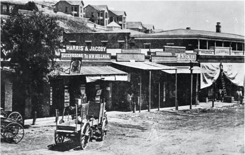 ภาพถ่ายมองไปทางทิศตะวันตกเฉียงเหนือของอาคาร Old Downey Block ประมาณปี 1870 ก่อนที่อาคาร Downey Block จะสร้างเสร็จในปี 1871: "Harris & Jacoby" ซึ่งเป็นบริษัทต้นกำเนิดของ Harris & Frank และ Jacoby Bros. และ M. Kremer ซึ่งเป็นบริษัทต้นกำเนิดของ City of Paris ห้างสรรพสินค้าแห่งแรกของเมือง