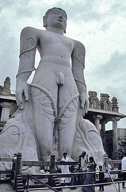 รูปปั้นหินสีเทาขนาดใหญ่ depicting ชายเปลือยกาย มีเถาวัลย์เลื้อยขึ้นไปถึงขาและแขน