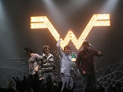 ชายสี่คนยืนอยู่ด้านหน้าเวทีด้วยกัน