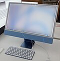 คอมพิวเตอร์ iMac รุ่นบางเฉียบสีน้ำเงินวางอยู่บนโต๊ะทำงาน