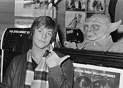 ภาพถ่ายของมาร์ค แฮมิลล์ในปี 1980 ขณะโปรโมตภาพยนตร์เรื่อง The Empire Strikes Back โดยชี้ไปที่หุ่นโยดา
