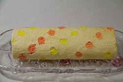 เค้กม้วนที่มีจุดสีส้มและสีเหลืองทั่วพื้นผิว