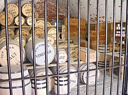 Derrière une grille de métal, des barils sont couchés, empilés en trois étages และ cette Pyramide se termine par des tonneaux de bOEuf salé